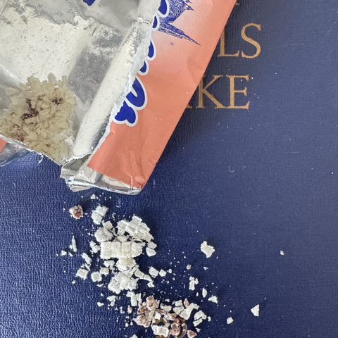 Blauer MEW-Band, mit einer aufgerissen, leeren Manner-Packung und Schnittenkrümel.