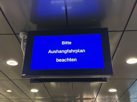 Digitaler Anzeigemonitor auf einem Bahnsteig: Bitte Aushangfahrplan beachten